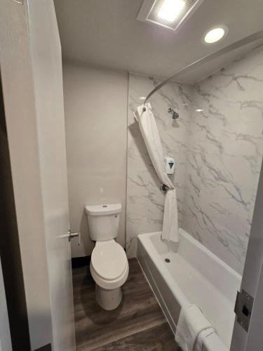 a white bathroom with a toilet and a bath tub at Hyland Inn near Legoland in Carlsbad
