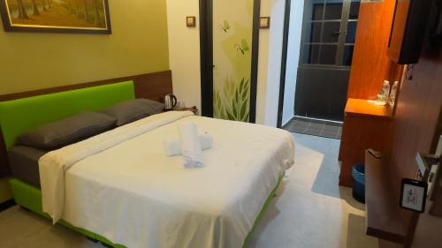 a bedroom with a bed with a green headboard at D GAYA HOTEL Cameron Highlands in Tanah Rata