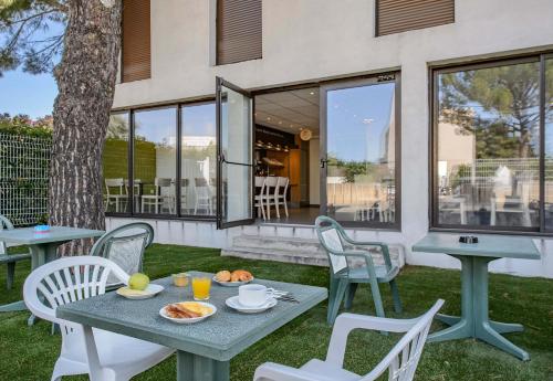 a table and chairs with food on it on a patio at B&B HOTEL Nîmes Ville Active, parking sécurisé gratuit in Nîmes