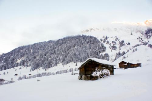 a cabin covered in snow in front of a mountain at Hotel Restaurant Walserhof in Medels im Rheinwald