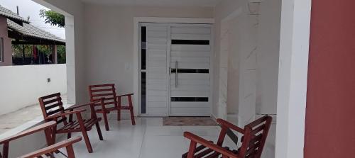 a group of chairs sitting on a porch with a door at Casa ideal 5 quatros sendo 3 suítes 2 km do centro in Bananeiras