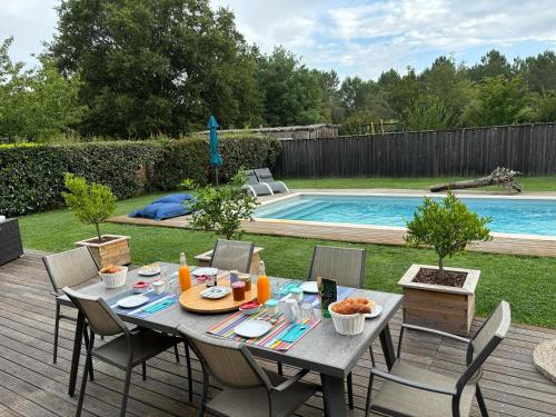 - une table et des chaises sur une terrasse à côté de la piscine dans l'établissement La Grange du Born, à Sainte-Eulalie-en-Born