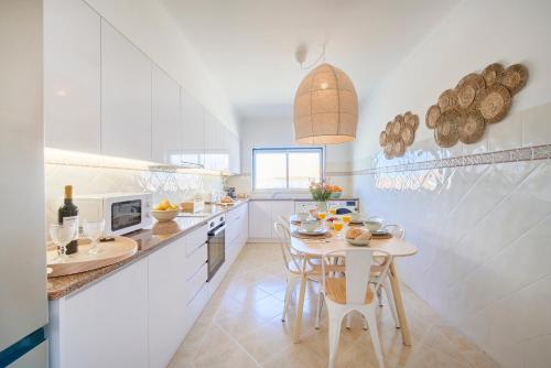 a white kitchen with a table and chairs in it at Vieira beach house apartment with sea view in Vieira de Leiria