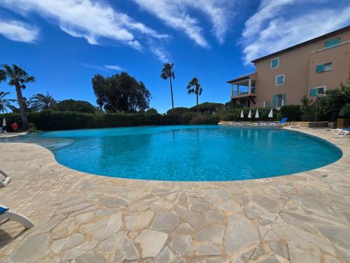 einen Pool mit blauem Wasser und Palmen in der Unterkunft Les rives des Issambres 1201 in La Garonnette-Plage