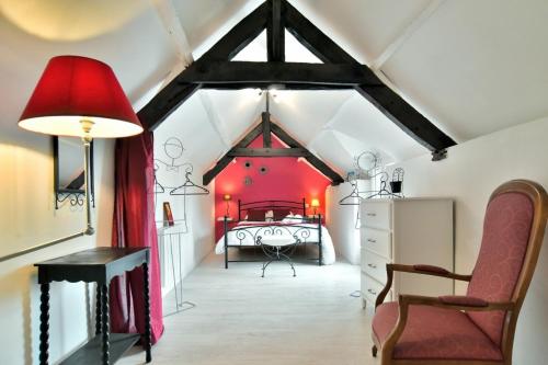Cette chambre mansardée comprend un lit rouge. dans l'établissement Maison Kalisol, à Pleine-Fougères