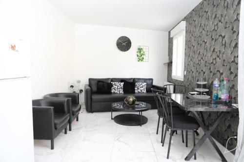 Una sala de estar con un sofá negro y una mesa. en Appartement Luxe Floral Stay 15 Min To CDG And Paris, en Le Bourget