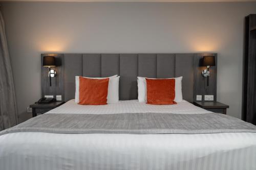 a bedroom with a large bed with orange and grey pillows at Hawkstone Park in Wem