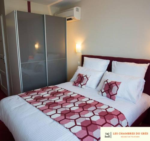 a bedroom with a large bed with a pink and white comforter at Les chambres du grès in Ambres