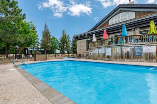 a swimming pool in front of a building with umbrellas at Blue Mountain The Parker Slopeside in Blue Mountains