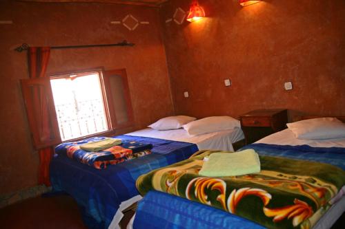a room with two beds and a window at Maison d'Hôte Valentine in Tinerhir