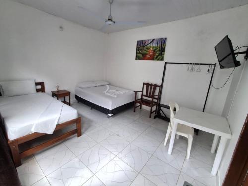 a room with two beds and a table and chairs at Heliconias Hotel in Leticia