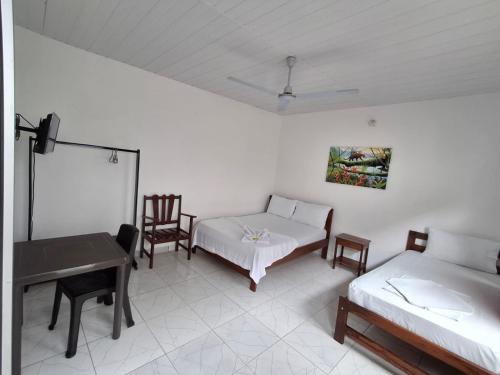 a room with two beds and a table and chairs at Heliconias Hotel in Leticia