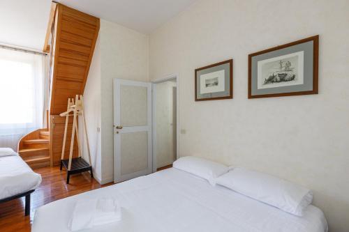 a bedroom with a white bed and two pictures on the wall at Dimora Alberoni in Ravenna