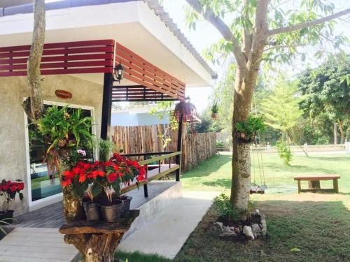 a house with potted plants and a bench in a yard at บ้านไร่แสงเดือน รีสอร์ท in Ban Kha