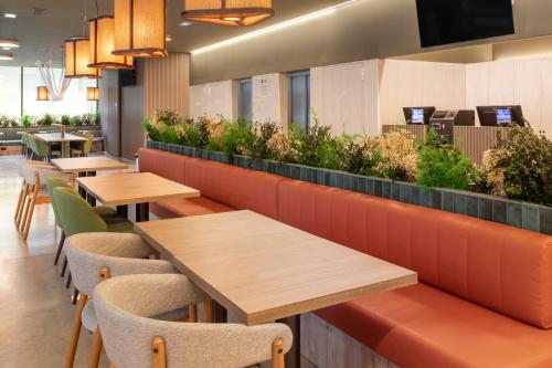 a restaurant with wooden tables and chairs and plants at B&B HOTEL Santo Tirso in Santo Tirso