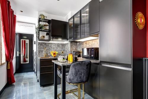 une cuisine avec des placards noirs et un tabouret de bar dans l'établissement TBS 328 - Lovely studio near Quartier Marais, à Paris