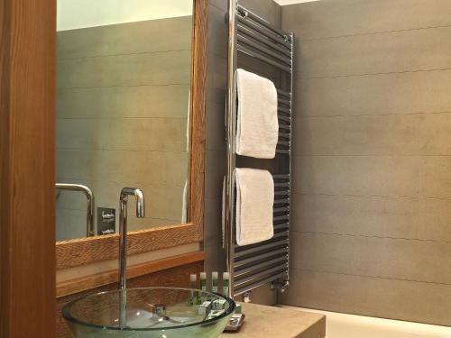 a bathroom with a glass sink and a mirror at Maloja Palace Residence Engadin-St Moritz CO2-Neutral in Maloja