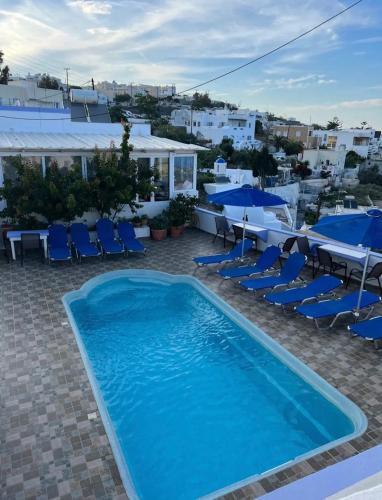 a pool with chairs and umbrellas on a resort at Stella Nomikou Apartments in Firostefani