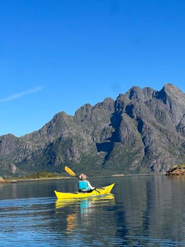 a person in a yellow kayak on a body of water at Spectacular mountain views with fireplace and jacuzzi in Svolvær