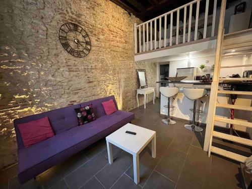 un soggiorno con divano viola e parete in pietra di Studio-mezzanine en centre ville proche Cathédrale a Orléans