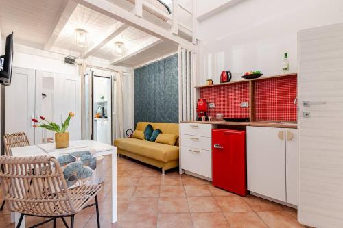 een keuken en een woonkamer met rode kasten en een bank bij Sabbie dell'Etna - Eleganza e Comfort nel Cuore di Catania con Parcheggio Privato in Catania