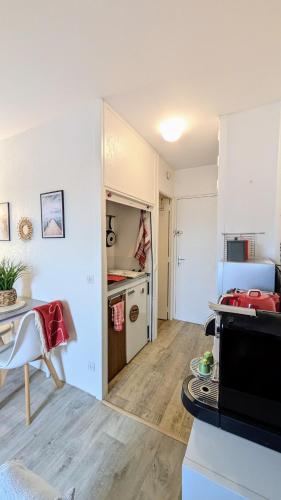 une cuisine avec des armoires blanches et une table dans une pièce dans l'établissement L'Étoile des Bains, Studio hyper centre Villers sur Mer, à Villers-sur-Mer