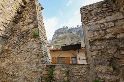 a building between two stone buildings with a mountain in the background at La Casa in Saint-Sorlin-en-Bugey