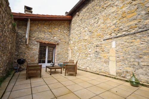 a patio with chairs and a stone wall at La Casa in Saint-Sorlin-en-Bugey