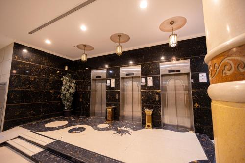 a bathroom with four elevators in a black tiled wall at Masar Al Aziziyah Hotel in Makkah