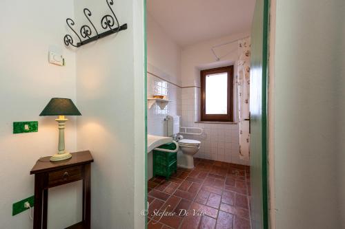 a bathroom with a toilet and a lamp on a table at Il Borgo Del Lupo Relax Family Apartments in Tuscany with Restaurant & Swimming Pool in Sarteano
