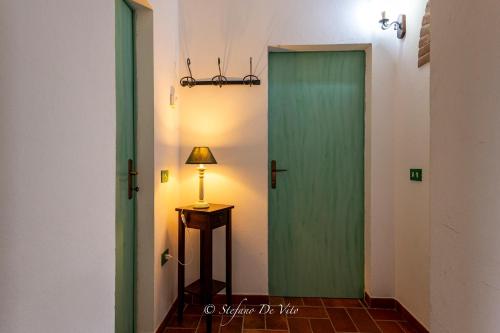 a green door in a hallway with a lamp at Il Borgo Del Lupo Relax Family Apartments in Tuscany with Restaurant & Swimming Pool in Sarteano