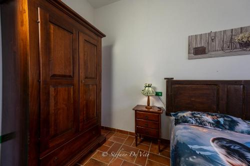 a bedroom with a bed and a wooden cabinet at Il Borgo Del Lupo Relax Family Apartments in Tuscany with Restaurant & Swimming Pool in Sarteano