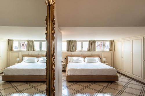 a bedroom with two beds and a mirror at Palazzo Porta Picta in Bergamo