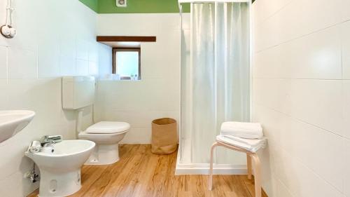 a white bathroom with a toilet and a sink at Sole's House in Verzuno