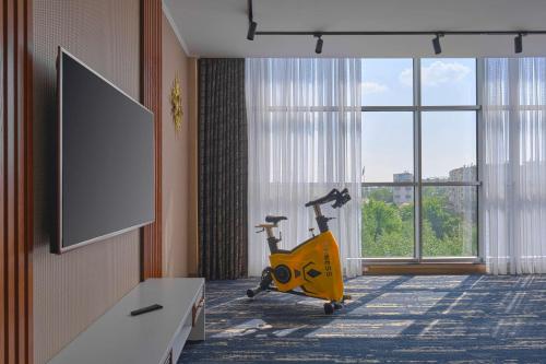 une chambre d'hôtel avec un tapis roulant et une grande fenêtre dans l'établissement Panarams Tashkent Hotel, a member of Radisson Individuals, à Tachkent
