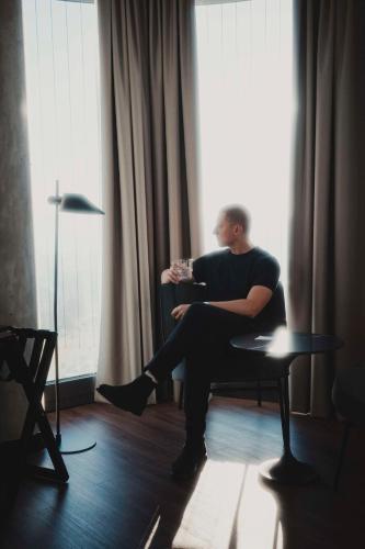 a man sitting in a chair with a glass of wine at Radisson Blu Hotel at Porsche Design Tower Stuttgart in Stuttgart