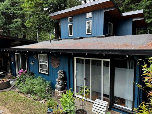 a blue house with a black roof at Humboldt Haven- Gorgeous Home for 10 w Gardens, Firepits, Forest & Bay Views in Arcata