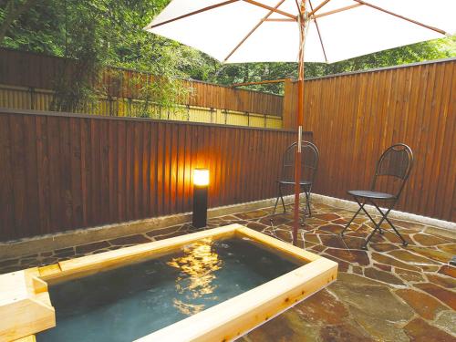 a hot tub with a table and chairs and an umbrella at Hotel Euro City in Nikko