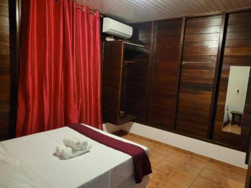 Habitación con cama y cortina roja en Domaine de la Matourienne, en Matoury