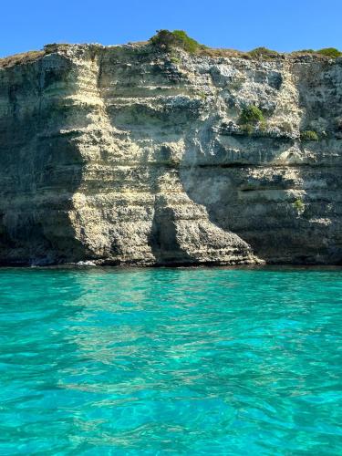 a rocky cliff next to the ocean with blue water at Molly's Home Otranto in Otranto