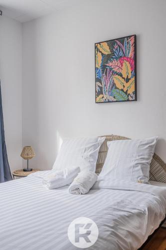 - un lit avec des draps blancs et une photo sur le mur dans l'établissement R Apparts T4 Sweet Home, à Grenoble