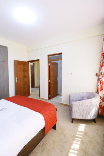 a bedroom with a bed and a couch and a chair at Rige's Homes 2Brm Furnished in Nairobi