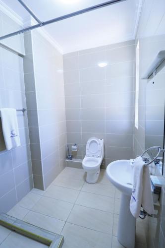 a white bathroom with a toilet and a sink at Rige's Homes 2Brm Furnished in Nairobi
