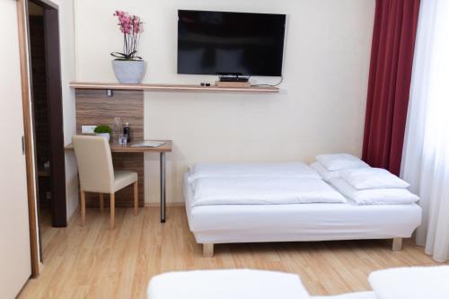 a living room with a bed and a table with a tv at HOTEL MARIA in Gramatneusiedl