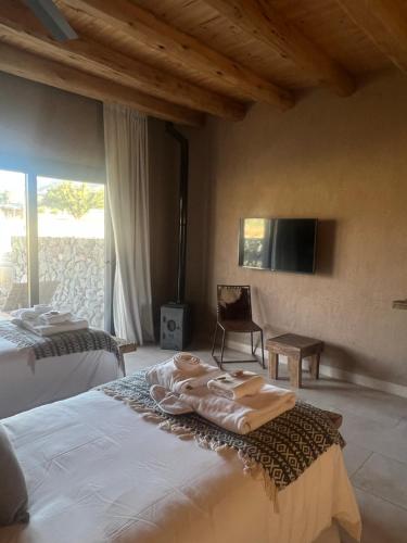 a bedroom with two beds and a flat screen tv at Rancho Adobe Eco Hotel in Tupungato