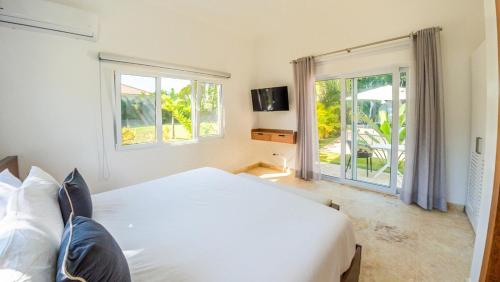 ein Schlafzimmer mit einem großen weißen Bett und Fenstern in der Unterkunft Villa Collie Luxury Retreat7 King Master Brmaid in Sosúa