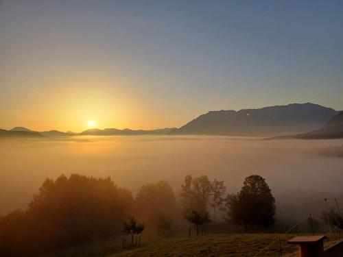 a misty sunrise with the sun rising over the mountains at Hölbinger Alm - Apartments in Anger