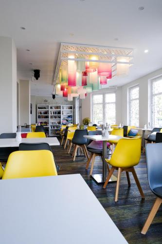 Un comedor con mesas y sillas amarillas. en Ostseehotel Baabe family & SPA, en Baabe
