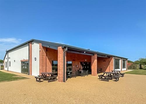 a building with picnic tables and benches in front of it at Willows Holiday Park in Withernsea
