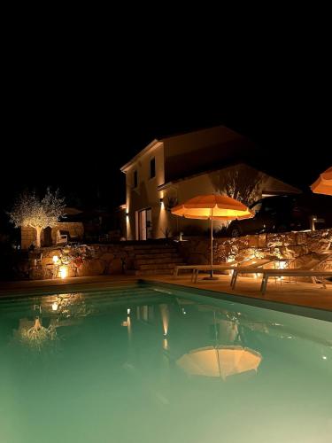 une piscine avec deux parasols et une maison dans l'établissement Villa with pool, absolute calm, à Plascassier